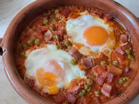 Huevos al plato con tomate, jamón y guisantes